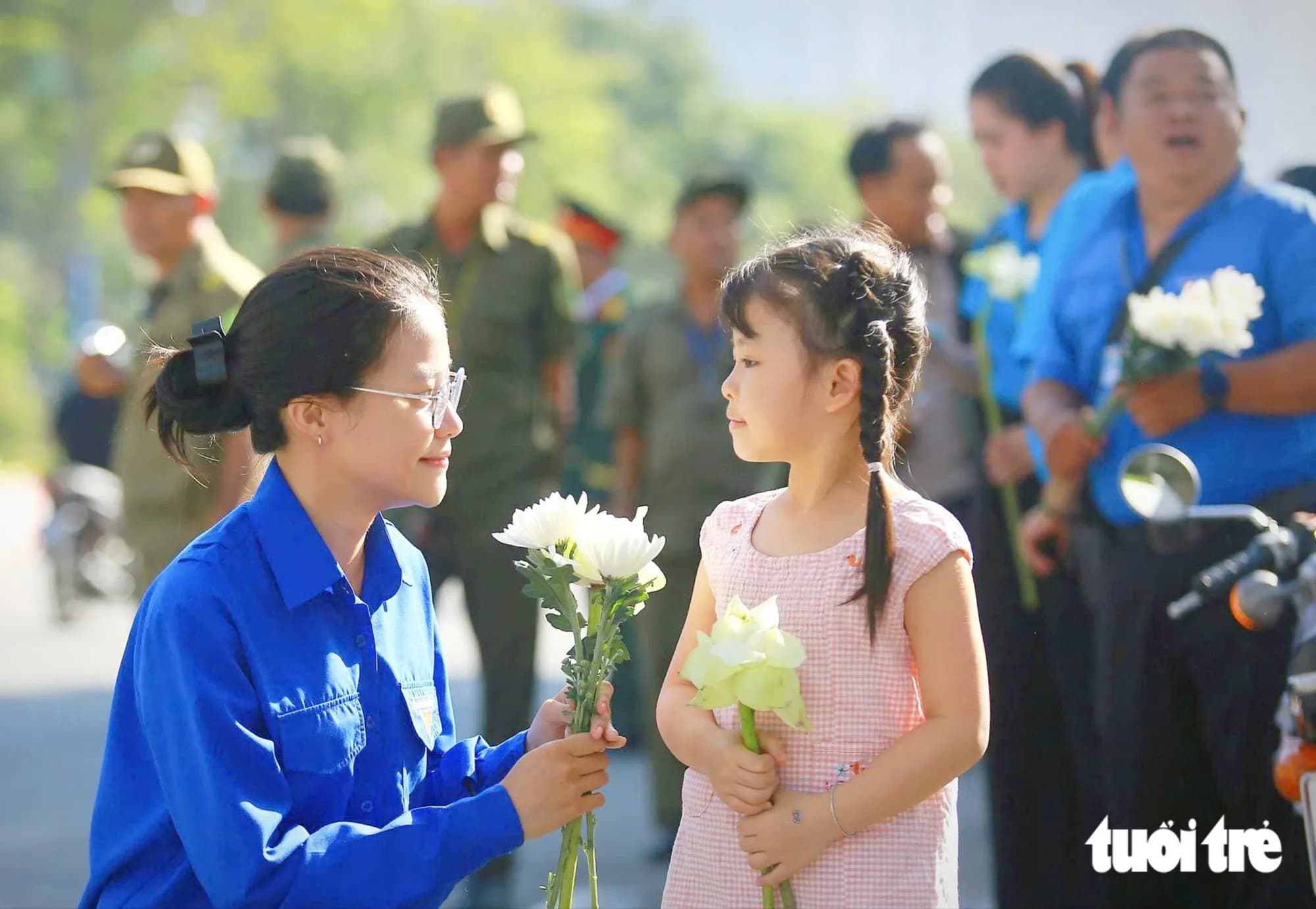 Người dân cầm hoa trắng đợi tiễn đưa các anh